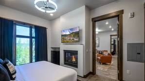 Quarto de hotel com cama, lareira, televisão e vista para a paisagem urbana.