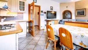 Une cuisine de taille réduite, équipée d’une cuisinière à gaz, de meubles en bois et d’un coin repas avec une table et des chaises.
