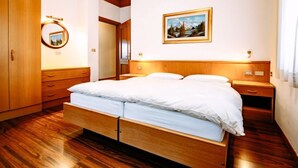 Une chambre à coucher avec un lit en bois, une table de chevet, un miroir et un tableau encadré accroché au mur.