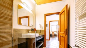 Une salle de bain moderne avec une douche à parois de verre, un lavabo blanc et un meuble-lavabo en bois.