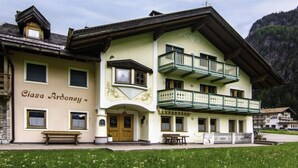 Un bâtiment à deux étages doté d’un balcon à l’étage supérieur, d’un banc à l’extérieur et d’une enseigne sur laquelle on peut lire « Ciasa Ardoney ».