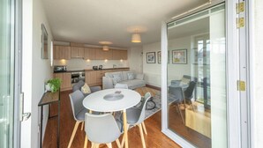 Un apartamento moderno con cocina, comedor y puerta de vidrio que da a un balcón.