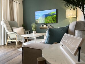 A living room with a modern design, featuring a sofa, a chair, a coffee table, and a flat-screen TV mounted on the wall. - Contemporary 2-Bedroom Rental Unit (Eagle Pass)