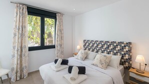 Quarto com cama, cortinas, janela e mesa de cabeceira com abajur.