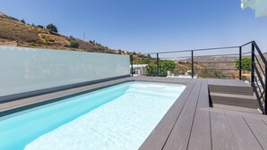 Uma piscina com deck de madeira e parede de vidro.