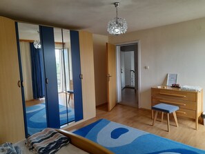 Makuuhuone, jossa on sänky, lipasto, penkki, peili ja kattokruunu.