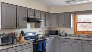 A kitchen with grey cabinets, a stove, a microwave, and a toaster.
