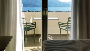 A room with a bed, a table, and two chairs. It has a view of a beach and a mountain. - Kallisto Rooms (Milos)