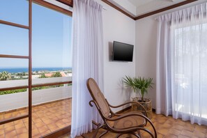 A balcony with a wicker chair, a potted plant, and a TV mounted on the wall. - Hilltopanorama (Chania)