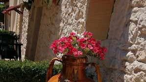 A large ceramic vase with flowers on a stone wall.