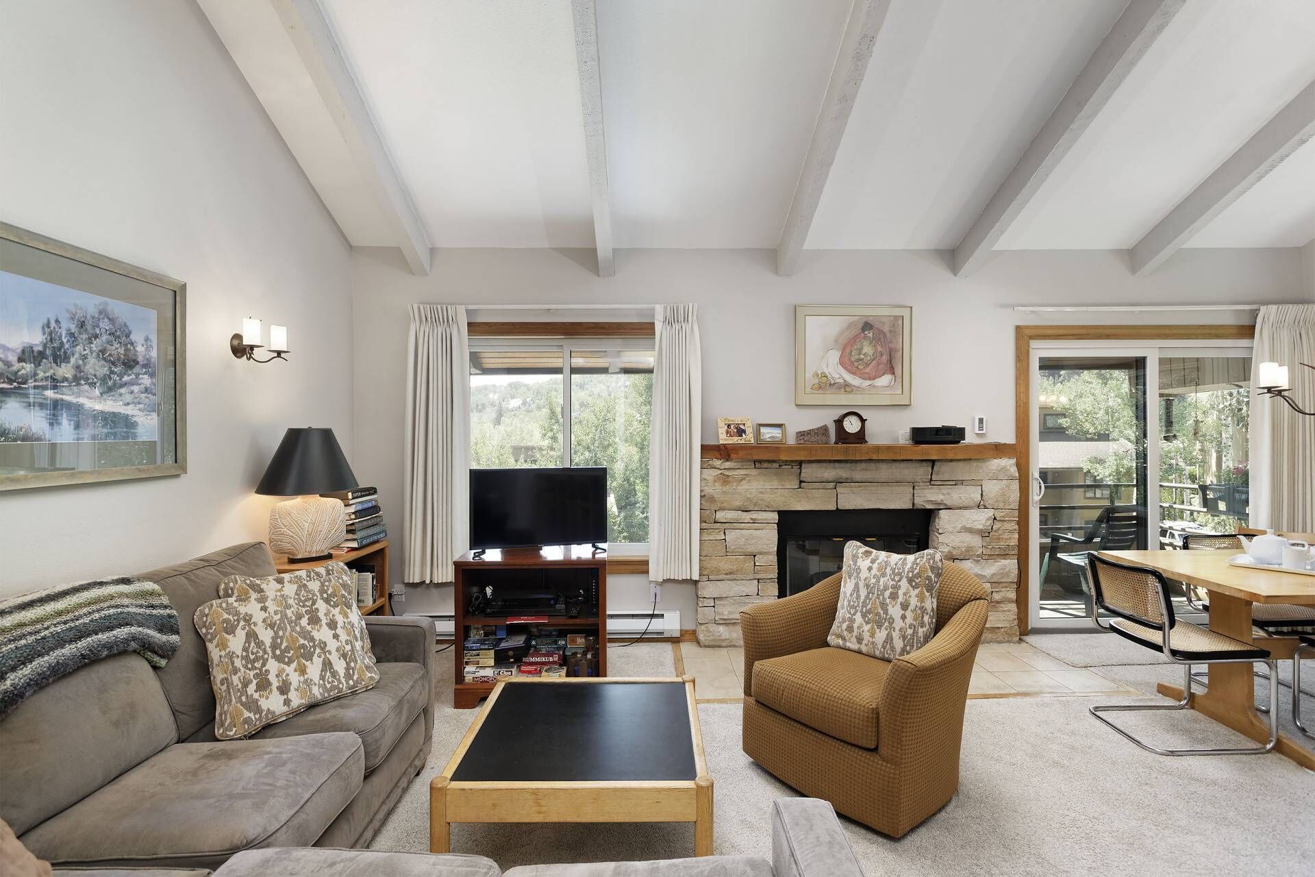 A living room with a fireplace, a television, and a dining area with outdoor seating.