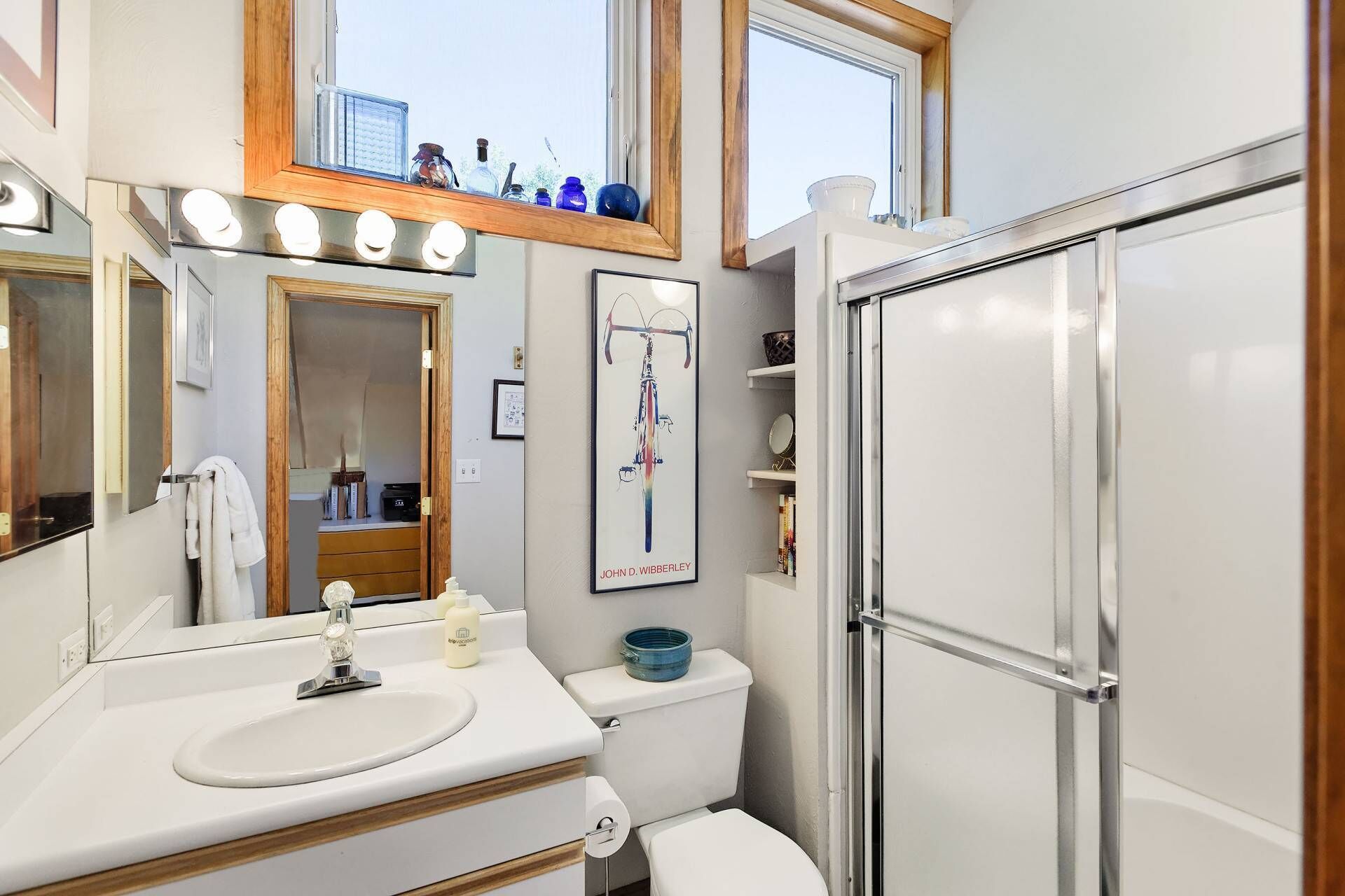 Un baño moderno con tocador, espejo y cabina de ducha.