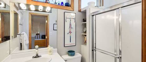 Un baño moderno con tocador, espejo y cabina de ducha.