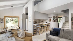 Amplia sala de estar con una mesa de comedor, un sofá y una escalera que sube a un piso superior.