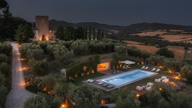 Una villa lussuosa con piscina, area salotto esterna e una torre.