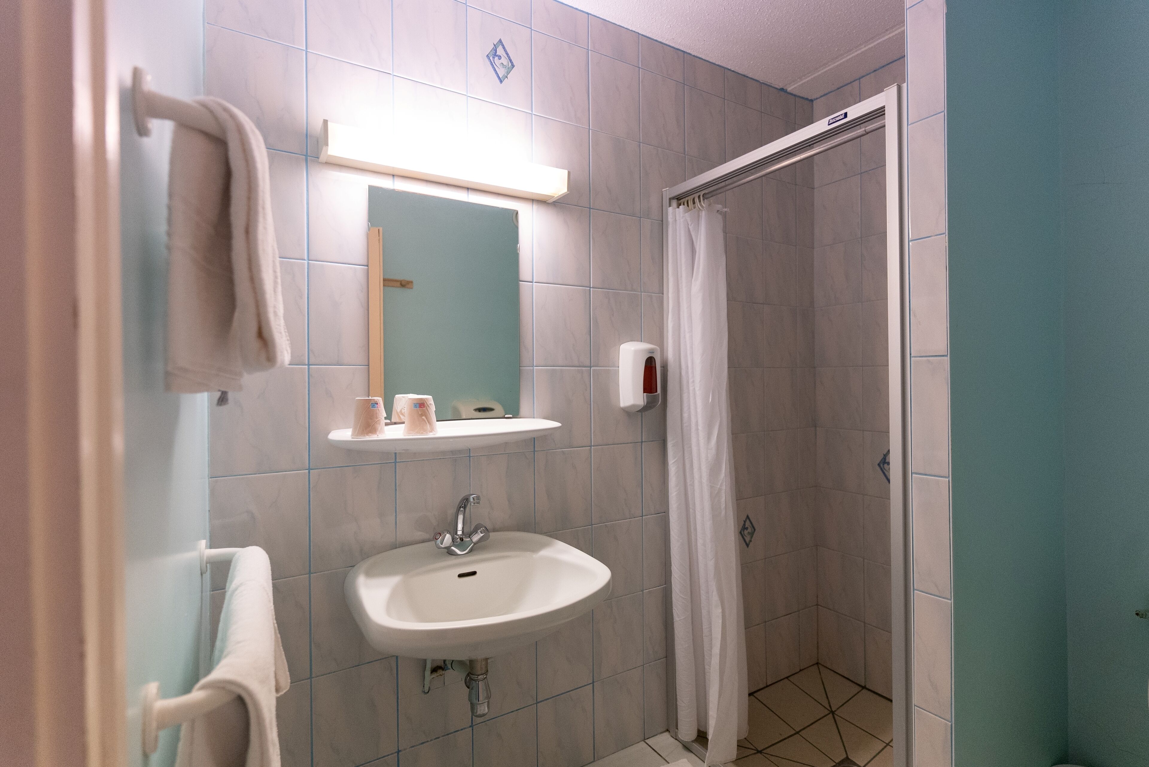 A bathroom with a sink, mirror, and shower curtain.