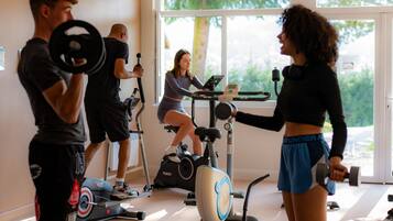 Et fitnesscenter med træningsmaskiner, vægte og et stort vindue.