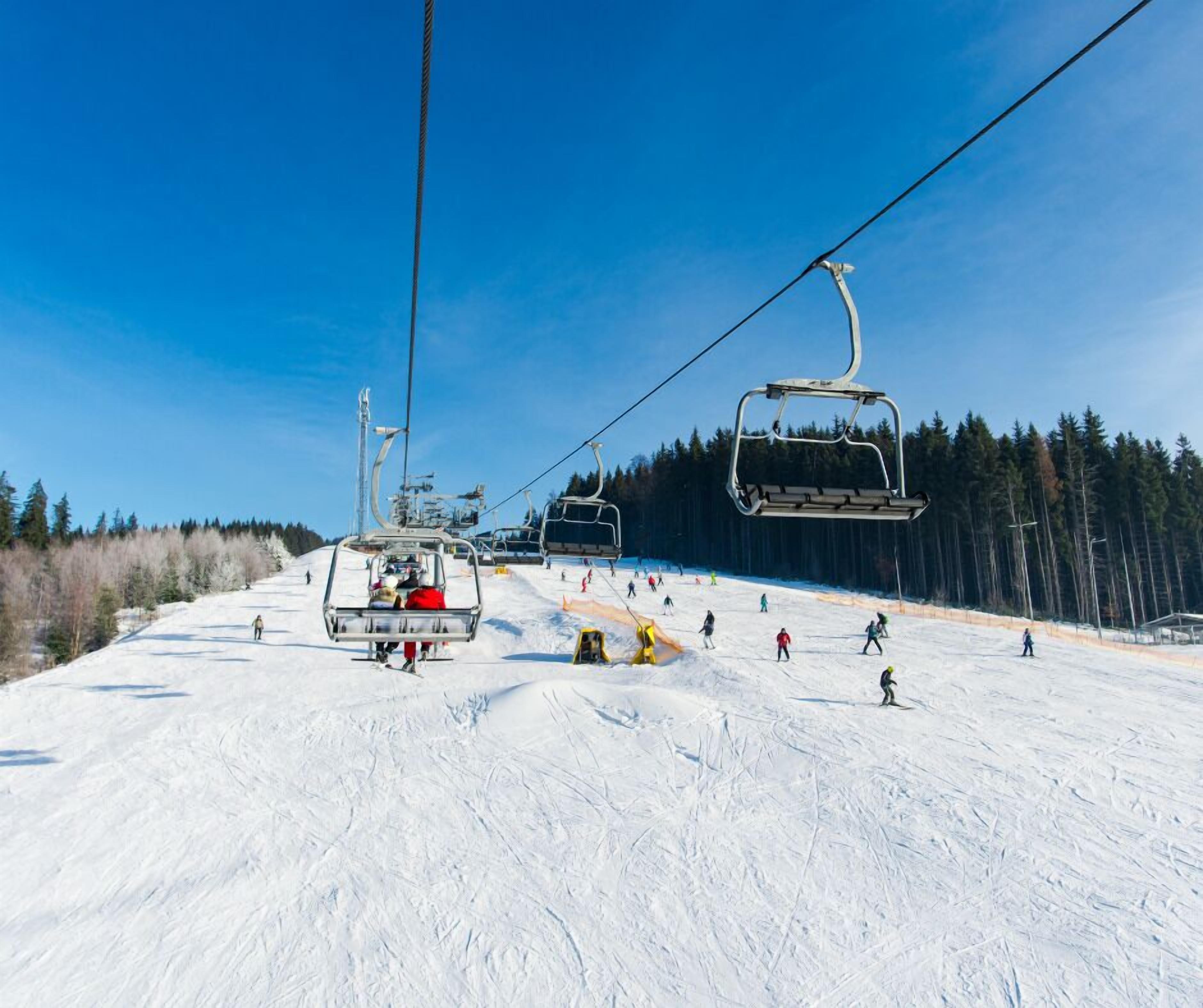 Eine Skiseilbahn mit Sesseln, die eine verschneite Piste hinauf- und hinunterfahren.