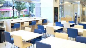 Un espace repas moderne avec des tables et des chaises, un four à micro-ondes et une vue sur la rue.