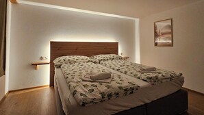 Un lit double avec une tête de lit en bois, deux tables de chevet et un tableau accroché au mur.