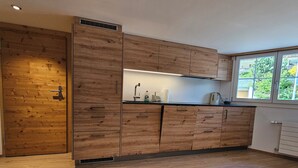 Une cuisine moderne avec des meubles de rangement en bois, un four encastré et une fenêtre qui laisse entrer la lumière naturelle.