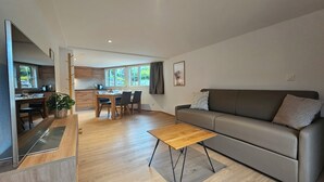 Un salon moderne avec un canapé gris, une table basse en bois et un coin repas comprenant une table et des chaises.