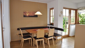 Ein Essbereich mit Holztisch und Stühlen, einer Bank, einer Hängeleuchte und einem Bild an der Wand.