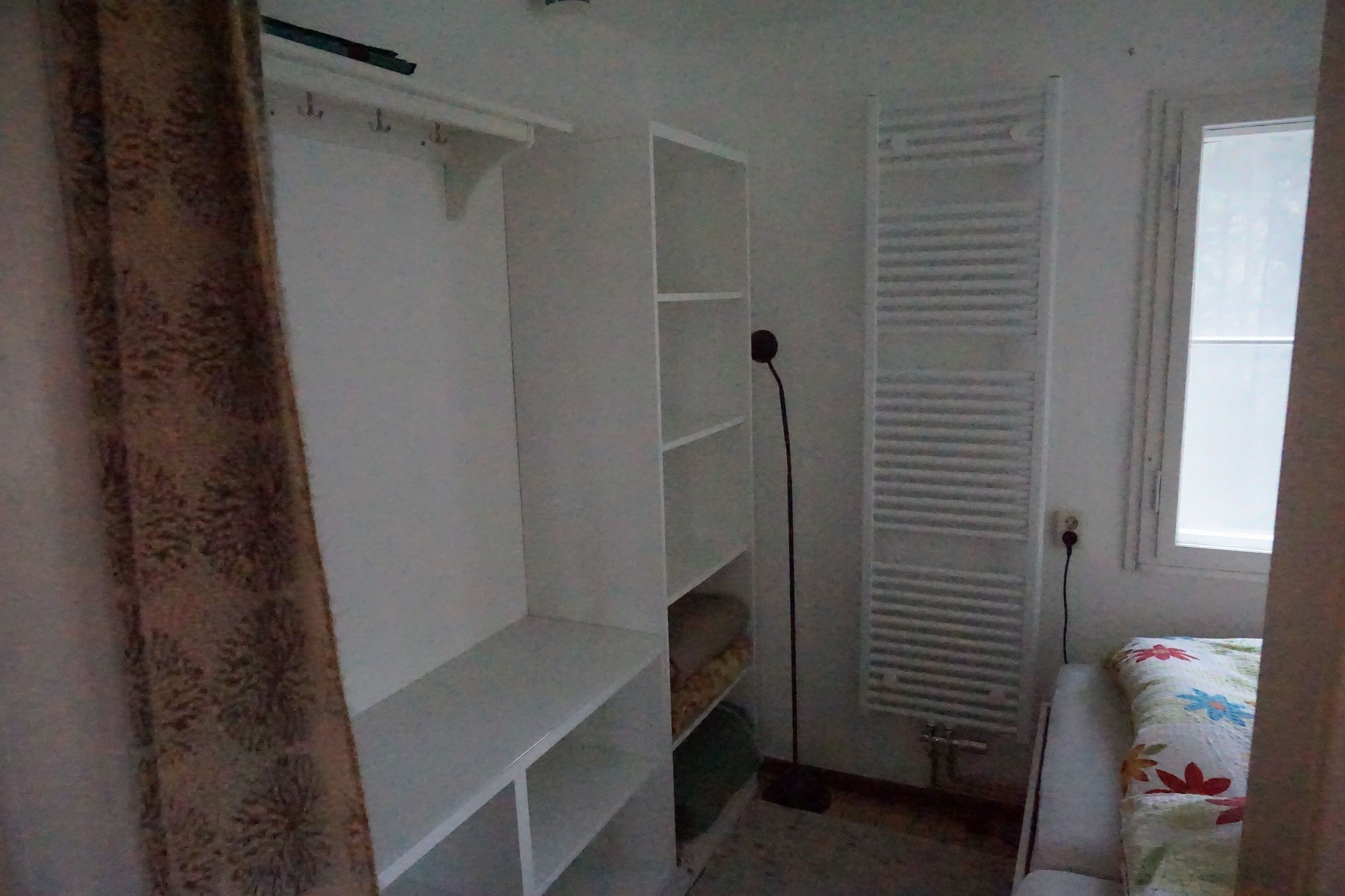 Une chambre à coucher avec un lit, un radiateur et une fenêtre.