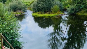 Een man vist in een rustige rivier met stenen trappen en houten leuningen.