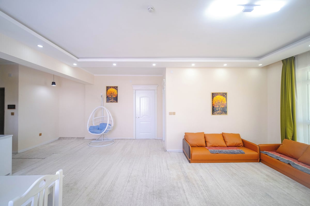 A modern living room with a sofa, a hanging chair, and artwork on the walls.