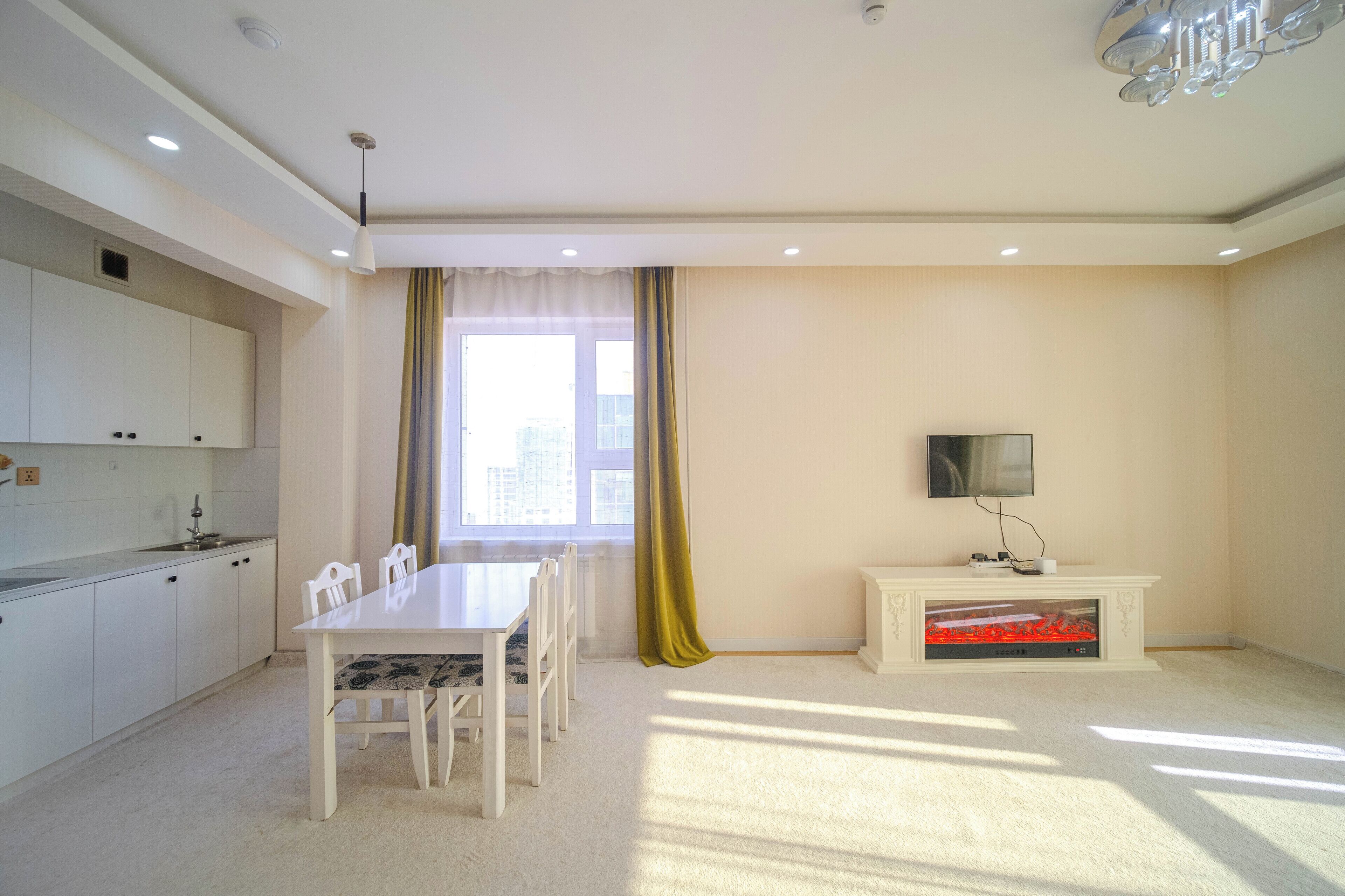 A modern living room with a dining table, chairs, a television, and a fireplace.