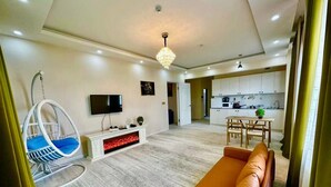 Ein modernes Wohnzimmer mit Sofa, Hängesessel, Kamin, Fernseher und Essbereich mit Tisch und Stühlen.
