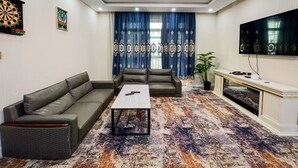 Ein Wohnzimmer mit Ecksofa, Couchtisch, Fernseher und Dartscheibe.