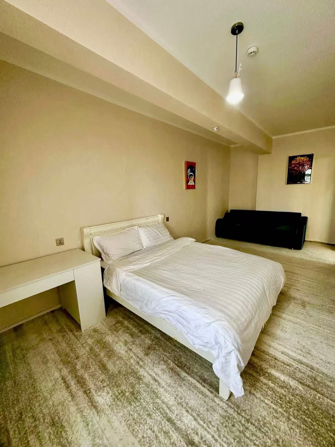 A bedroom with a bed, a desk, and a TV.