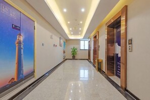 A hotel corridor with a polished floor, a large poster of a lighthouse, and an elevator. - LANOU Hotel (Haiyan Science City) (Haiyan)