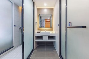 Un bany modern amb una cabina de dutxa de vidre, un lavabo blanc i un mirall a sobre.