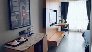A hotel room with a bed, a desk with a chair, a TV, a framed picture on the wall, and a window with curtains. - LANOU Hotel (Haiyan Science City) (Haiyan)