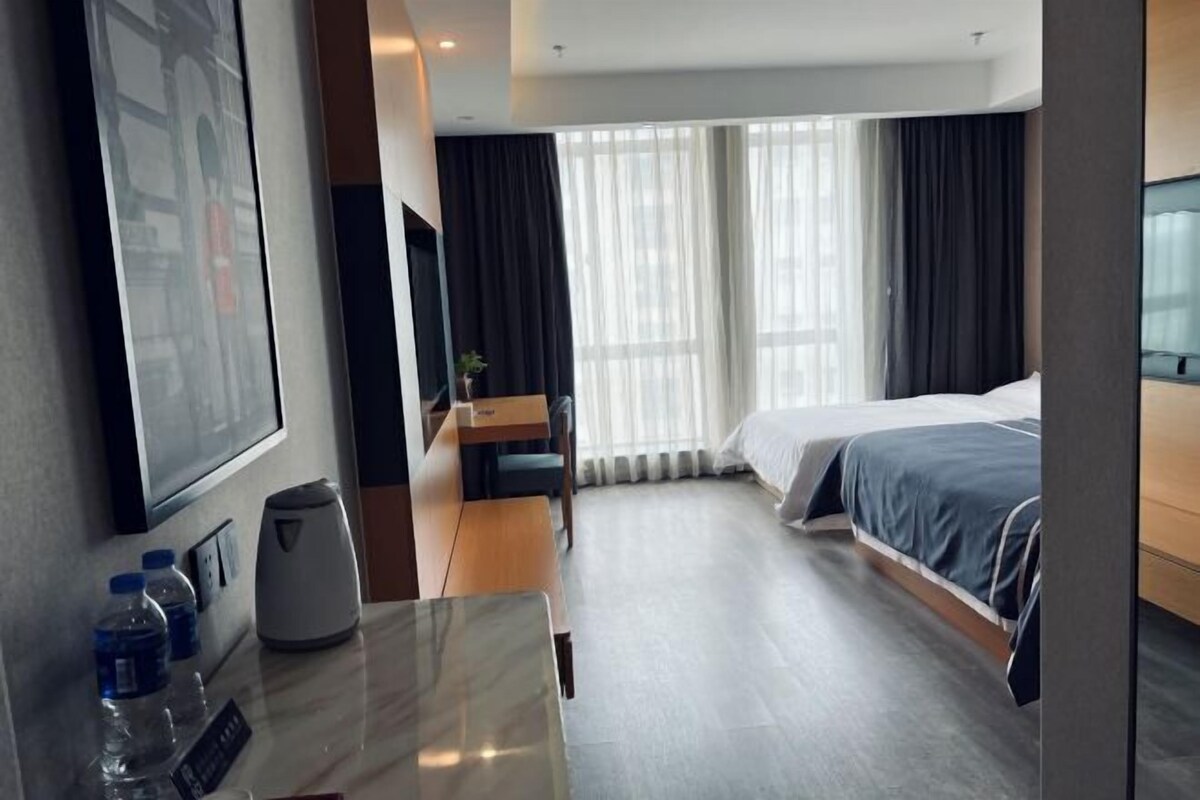 A hotel room with a bed, a desk with a chair, a coffee maker, and a TV.