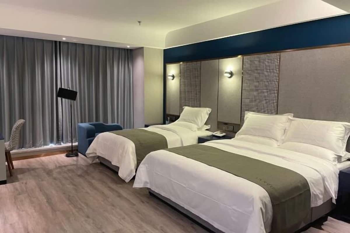 A hotel room with two beds, a large window with curtains, a flat-screen TV, and a modern design.