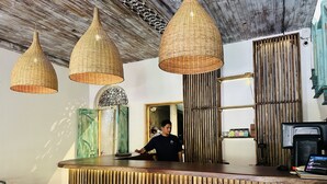 A reception area with a wooden reception desk, three woven pendant lights, and a bamboo wall. - Moi Galle Fort by DBI (Galle)