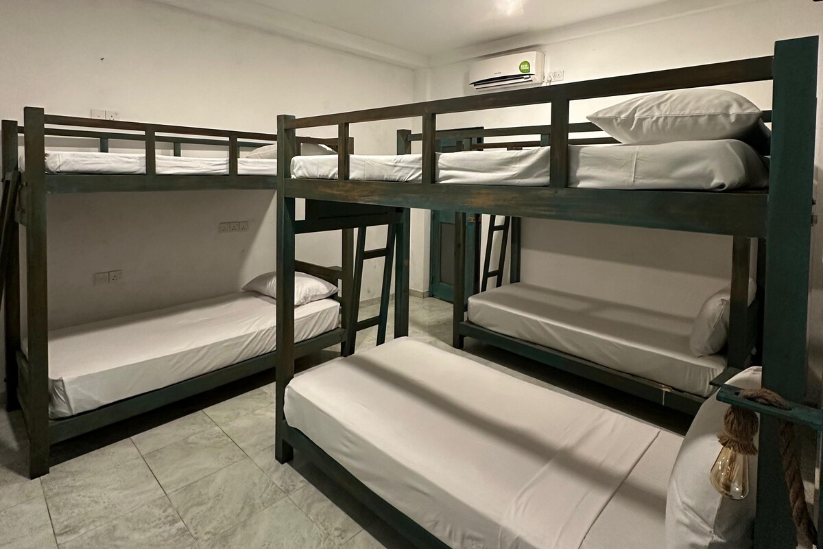 Een slaapzaal met stapelbedden, een plafondlamp en een airconditioning.