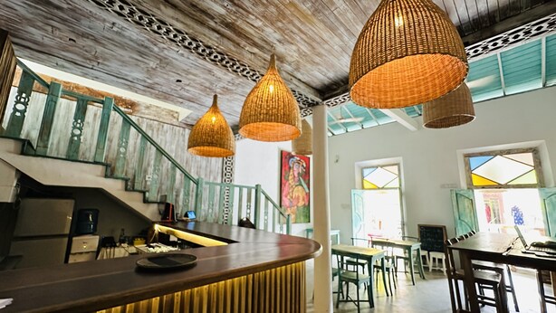 A restaurant with a wooden ceiling, hanging wicker lamps, and a staircase with green railings. - Moi Galle Fort by DBI (Galle)