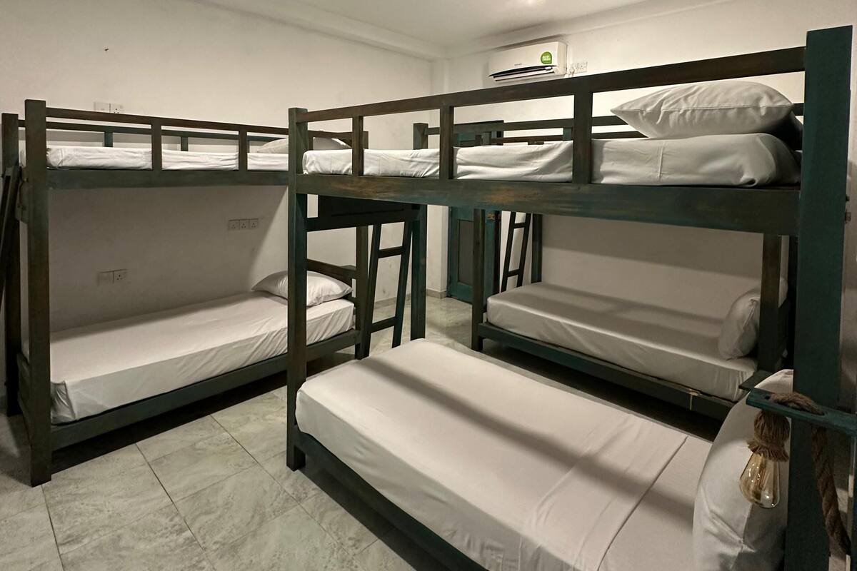 Een slaapzaal met stapelbedden, een plafondlamp en een airconditioning.