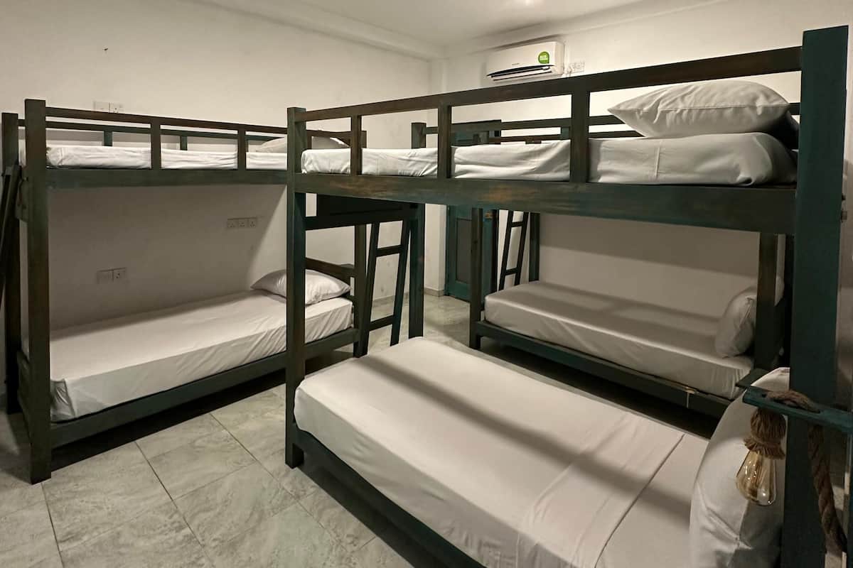 Um quarto de dormitório com beliches, uma lâmpada no teto e um aparelho de ar condicionado.