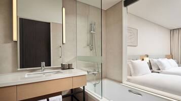 Un baño de hotel moderno con un espejo grande, un lavamanos, una ducha y una bañera.
