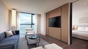 Een moderne hotelkamer met een bank, fauteuils, een salontafel, een televisie en een bed.