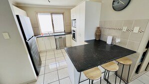 A kitchen with a black countertop, stainless steel appliances, and a window with a mesh screen. - Sandstone Point Family home, Bribie beaches, pet friendly  (Sandstone Point)