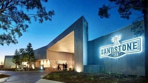 A modern hotel with a prominent 'SANDSTONE' sign, featuring a lighthouse logo. - Sandstone Point Family home, Bribie beaches, pet friendly  (Sandstone Point)
