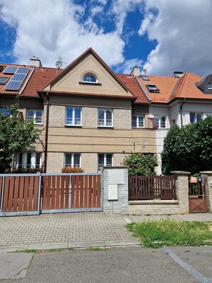 Um edifício residencial de vários andares com fachada de tijolos, várias janelas e entrada com portão.