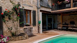 Ein Gebäude aus Stein mit Swimmingpool, Sitzgelegenheiten im Freien und einer überdachten Terrasse.